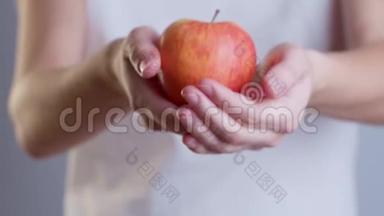 一个女人拿着一个红苹果的特写镜头